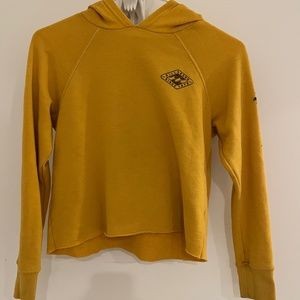 Yellow cropped hoodie, shirt billabong symbol and palm trees running down arm